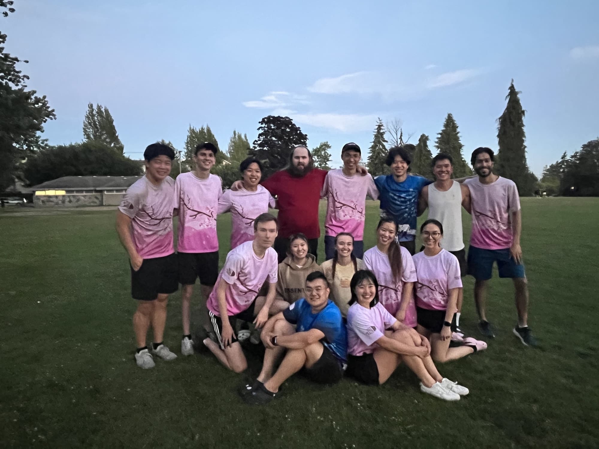 Katrina's frisbee team in matching pink shirts posing on a field